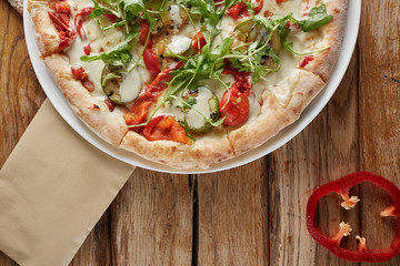 Tasty vegetarian pizza with vegetables, paper and basil.