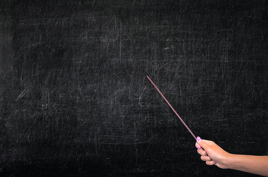 The Teacher Shows A Pointer To An Empty School Chalkboard With Copy Space. Theme Of The Lesson, Education Concept.