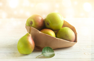 Paper bag and ripe pears on wooden table
