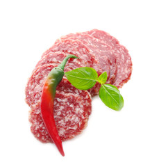 Delicious sliced sausage with chili pepper and basil on white background
