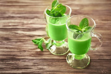 Glasses of green healthy juice with mint on wooden table