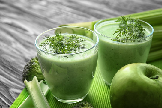 Glasses of green healthy juice with ingredients on wooden table