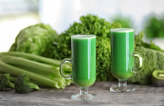 Glasses of green healthy juice with vegetables on wooden table
