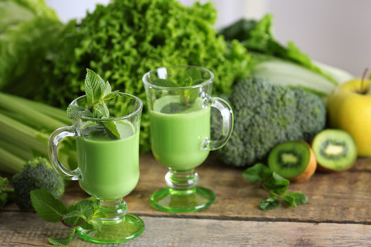 Glasses of green healthy juice with vegetables and fruits on wooden table