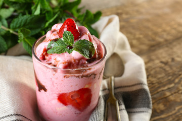 Glass with tasty strawberry yogurt ice cream on wooden table
