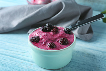 Bowl with tasty blackberry yogurt ice cream on wooden table
