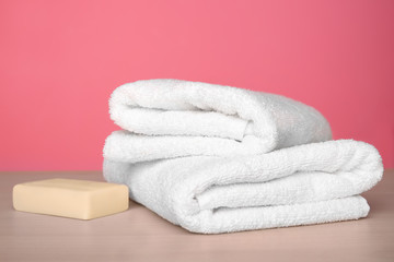 Clean towels on table against color background