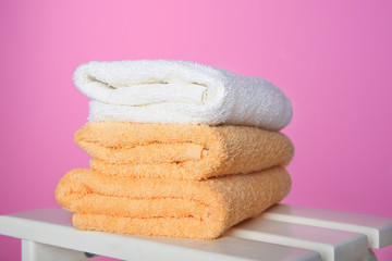 Clean towels on table against color background