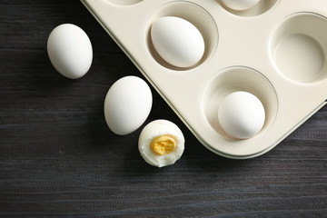 Fototapeta na wymiar Muffin tin and hard boiled eggs on wooden table