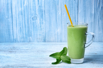 Glass of green healthy juice with mint on wooden table