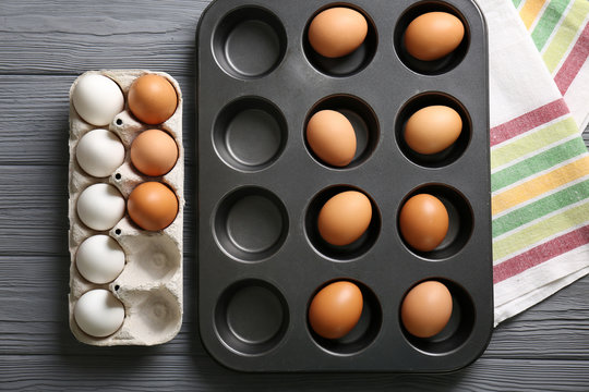 Muffin tin and holder with hard boiled eggs on wooden table