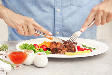 Young man eating delicious ribs in restaurant