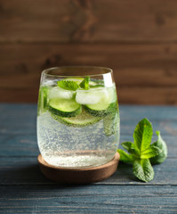 Delicious refreshing water with mint and cucumber in glass on wooden table