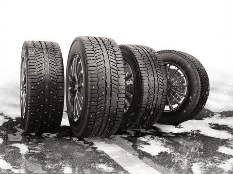 Four car tires rolling on a snow-covered road.