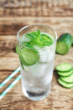 Delicious refreshing water with mint and cucumber in glass on wooden table