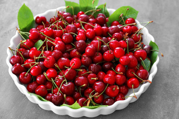 Plate with fresh ripe cherries on table