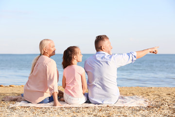 Cute girl with grandparents on sea beach