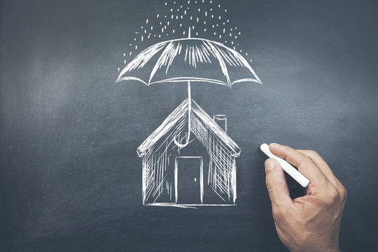 Businessman Drawing Umbrella Over House On Board