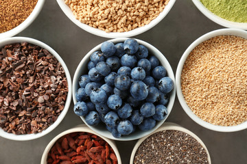 Composition with assortment of superfood products in bowls on grey background, closeup