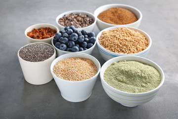 Composition with assortment of superfood products in bowls on grey textured background