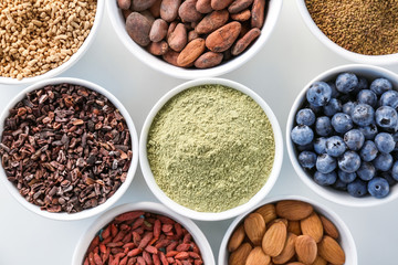 Composition with assortment of superfood products in bowls on white background, closeup
