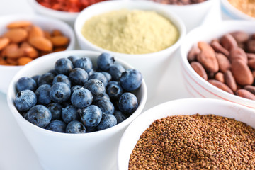 Composition with assortment of superfood products in bowls on white background, closeup