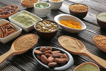 Composition with assortment of superfood products in bowls and spoons on wooden background