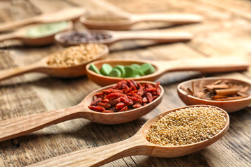Composition with assortment of superfood products in wooden spoons on table
