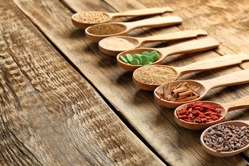 Composition with assortment of superfood products in wooden spoons on table