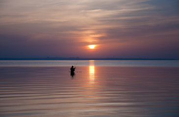 Silhouette of fishermen on a sunset background