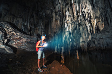 Young woman explores cave with stalagmites and stalactites