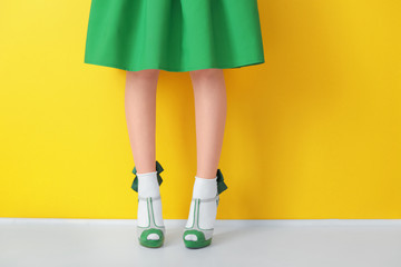 Female legs in green high heel shoes and socks on color background