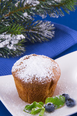 Christmas cupcake with bilberry and Christmas tree on a blue background.