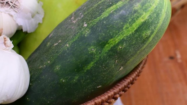 Cucumbers, onions, garlic and pepers in wicker basket on brown backround. Rotating vegetables