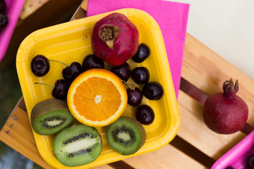 Fruits on the plate, orange, kiwi, pomegranate, grape, cherry. Photo decoration. Romantic