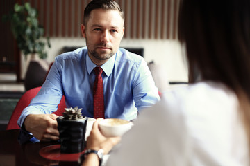 Teamwork. Businessman and businesswoman sitting at table in coffee shop and discuss business plan. On table is laptop, tablet, smartphone, notebook, cup of coffee.Business meeting of partners in cafe.