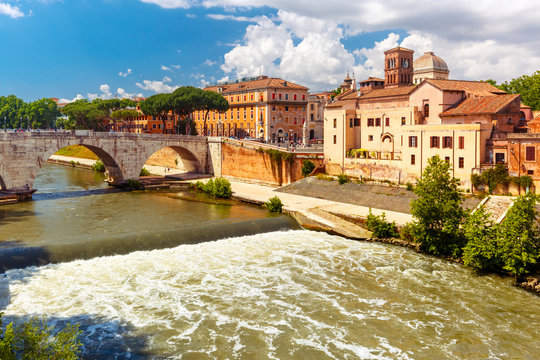 View of the Tiber island or Isola Tiberina with Pons Cestius and Basilica of St Bartholomew in sunny day, Rome, Italy