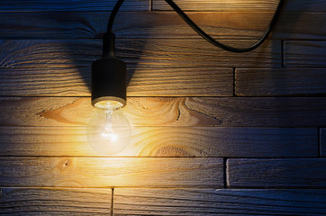 Burning incandescent bulb on a wooden background. A layout with an empty space for your text top view