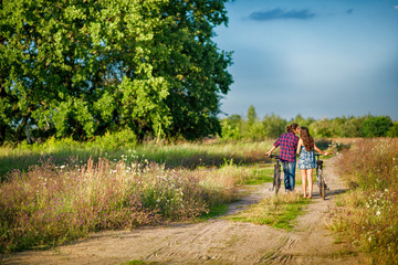 Obraz premium couple riding bikes in the hands of a girl a bouquet of wildflowers