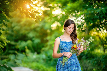 young girl with bouquets of flowers in the park at sunset