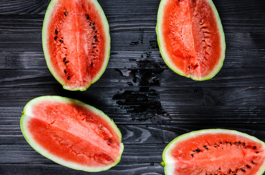 Background of fresh ripe watermelon slices on black wooden table. Top view.