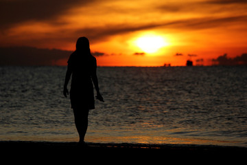 silhouette of woman walking on the beach