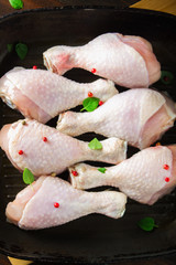 Raw chicken legs in a frying pan on a wooden table. Meat ingredients for cooking. Top view.