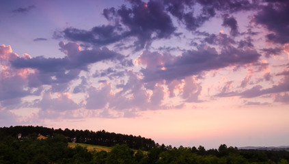 Colorful sunset clouds above the hill