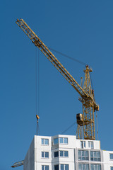 Tower crane constructing white house of prefabricated blocks