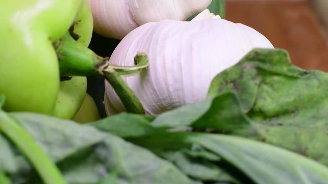 Cucumbers, onions, garlic and pepers in wicker basket on brown backround. Rotating vegetables. Closeup