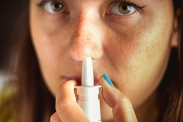 The girl uses a spray for her nose. Treatment of colds, flu.