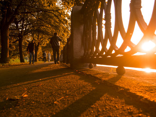 Shadows on the promenade. Autumn sunset on the embankment with people.