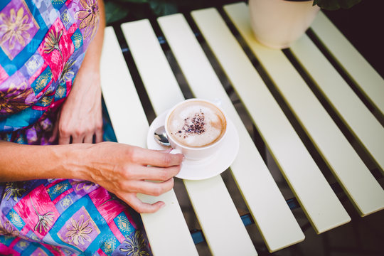 Close up image of woman shaking her favorite tasty chocolate cappuccino at cute cafeteria, wearing retro white skirt and accessorizes. Shabby chic style.