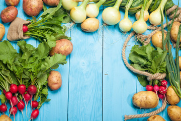 Raw radishes and potatoes on a blue wooden background